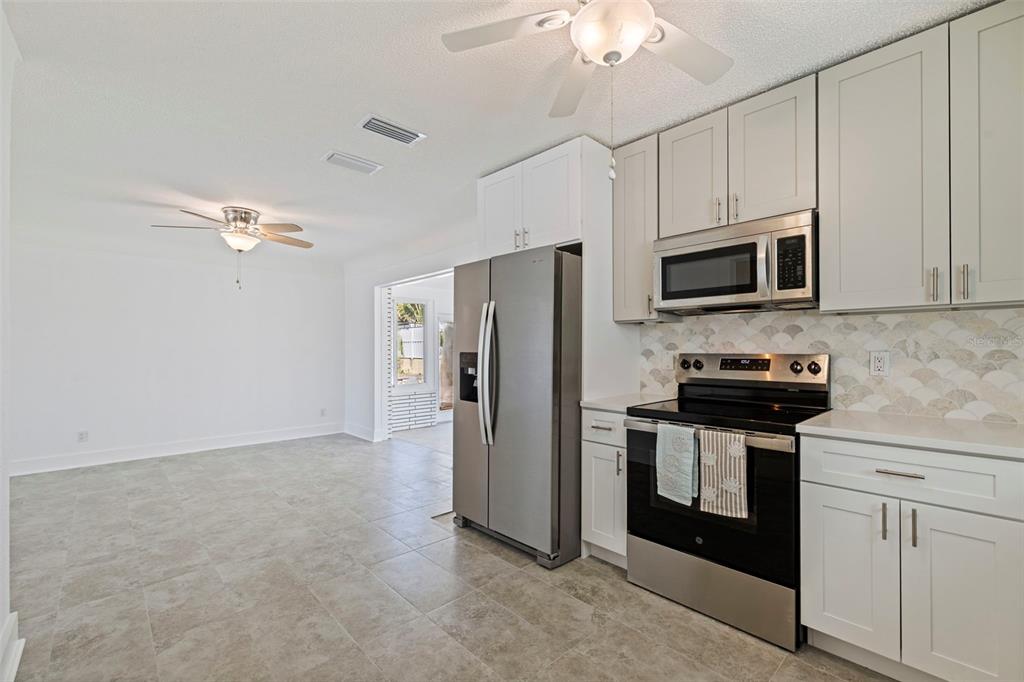 176 175th Avenue East Redington Shores, FL 33708 - Photo 11 of 37 a kitchen with stainless steel appliances granite countertop a refrigerator a stove a microwave oven with white cabinets