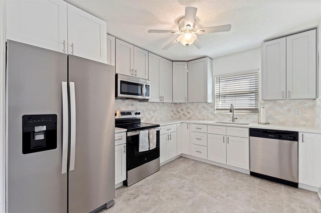 176 175th Avenue East Redington Shores, FL 33708 - Photo 10 of 37 a kitchen with stainless steel appliances granite countertop a refrigerator a stove a sink a stove with white cabinets