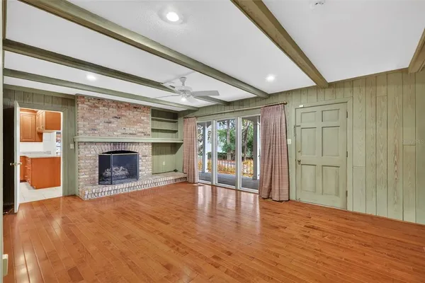 a view of an empty room with wooden floor fireplace and a window