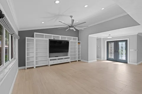 an empty room with a flat screen tv and ceiling fan