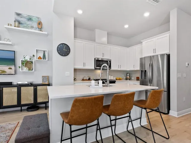 a kitchen with stainless steel appliances a dining table chairs refrigerator and sink