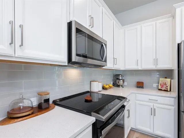 a kitchen with stainless steel appliances granite countertop a sink stove and white cabinets