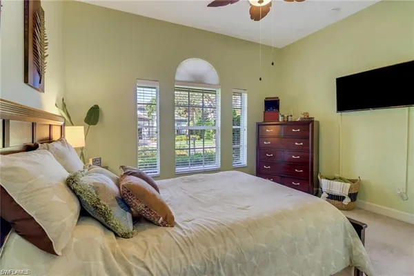a bedroom with a bed and a flat tv screen on dresser