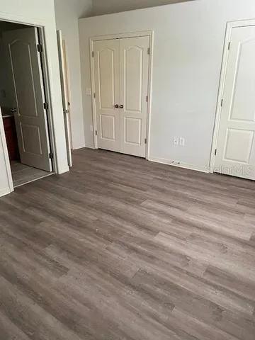 an empty room with wooden floor and entrance