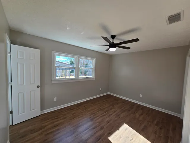 a view of wooden floor and a chandelier fan in a room
