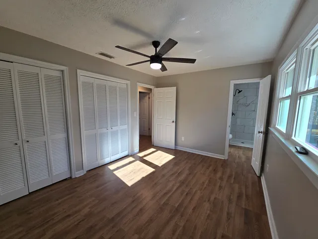 a view of empty room with wooden floor and fan