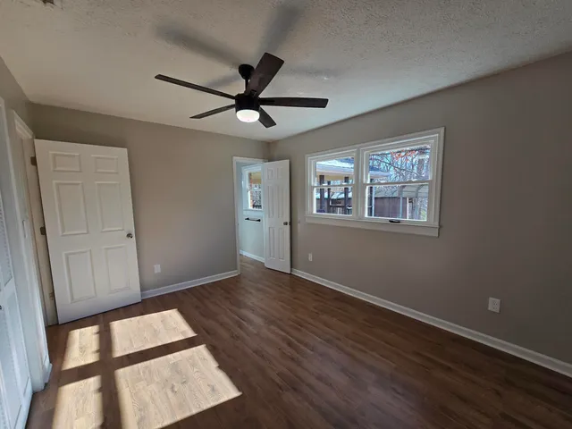 a view of an empty room with a window and wooden floor