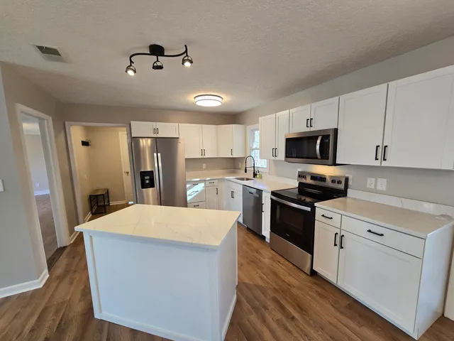 a kitchen with kitchen island a sink stainless steel appliances and cabinets