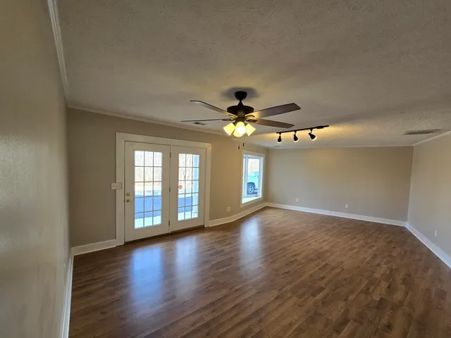 a view of an empty room with window and wooden floor