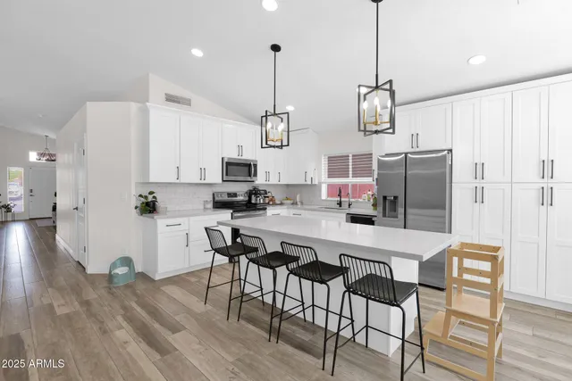 a kitchen with stainless steel appliances a dining table chairs refrigerator and sink