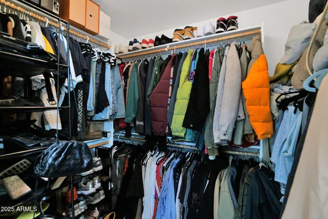 a view of walk in closet with clothes and shoes