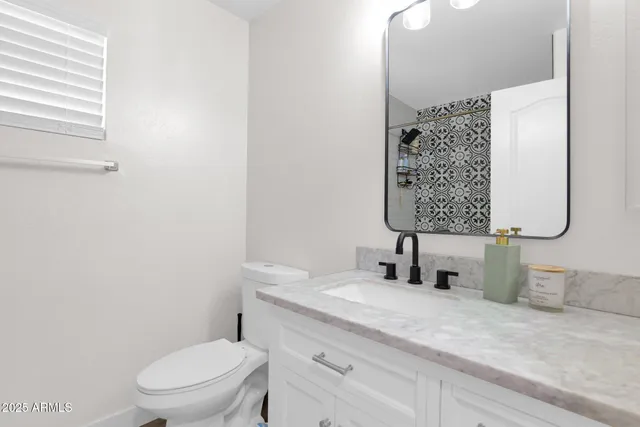 a bathroom with a granite countertop toilet sink and mirror