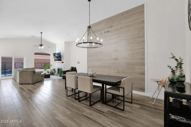 a dining room with wooden floor a chandelier a glass table and chairs