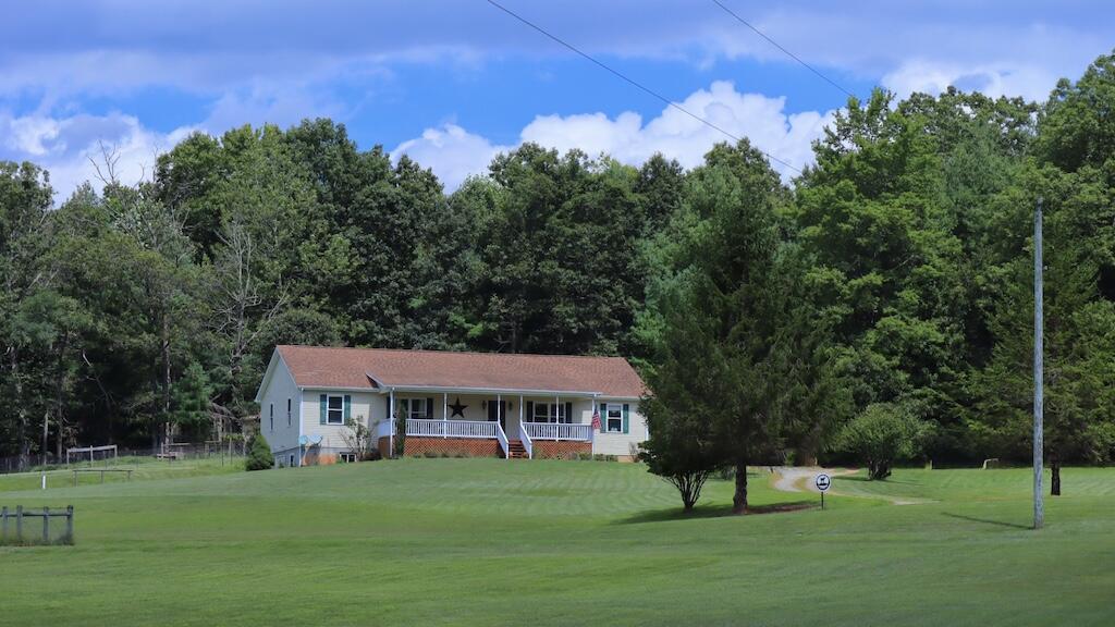 a view of a big house with a big yard and large trees