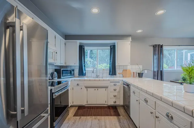 a view of a kitchen with white cabinets and wooden floor