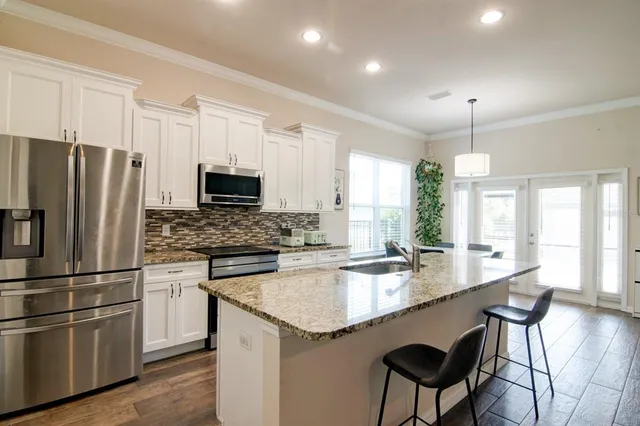 a kitchen with granite countertop stainless steel appliances a stove a sink a microwave a dining table and chairs