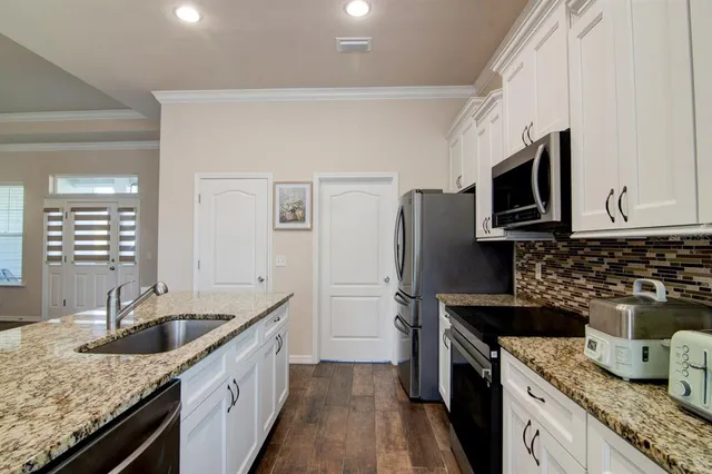 a kitchen with granite countertop kitchen island a sink stainless steel appliances and cabinets