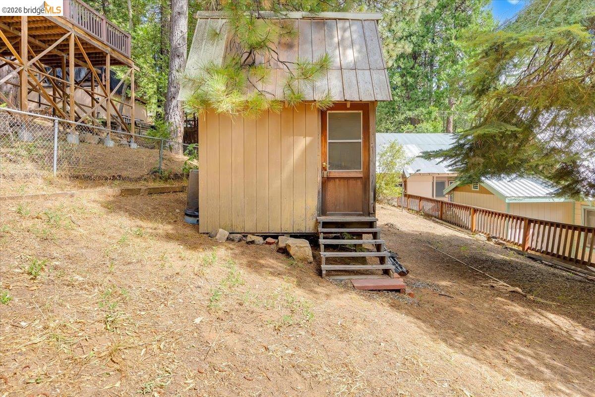 26144 Long Barn Road Long Barn, CA 95335 - Photo 36 of 42 Detached storage building with a wood door, multiple steps, and a pitched roof