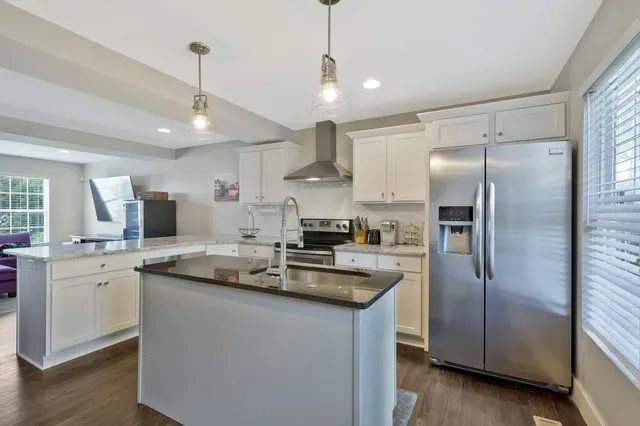 a kitchen with stainless steel appliances granite countertop a sink a stove a refrigerator and island with wooden floor