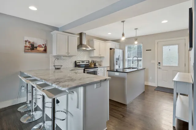 a kitchen with stainless steel appliances granite countertop a kitchen island a stove a table and chairs in it