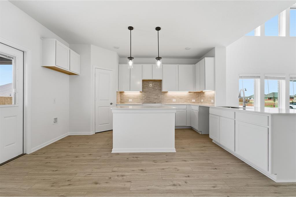 228 Charismatic Road Waxahachie, TX 75165 - Photo 11 of 23 a kitchen with kitchen island granite countertop a sink cabinets and wooden floor