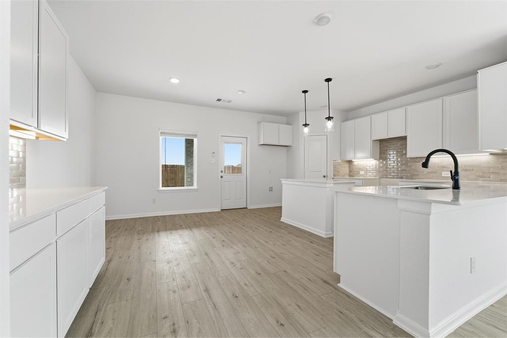 228 Charismatic Road Waxahachie, TX 75165 - Photo 10 of 23 a kitchen with kitchen island white cabinets and sink