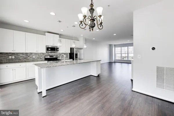 a kitchen with stainless steel appliances granite countertop a refrigerator a stove top oven a sink dishwasher and white cabinets with wooden floor