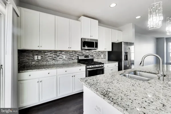 a kitchen with granite countertop white cabinets and stainless steel appliances