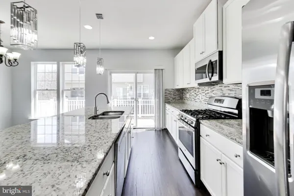 a large kitchen with granite countertop a stove top oven a sink a counter space and stainless steel appliances