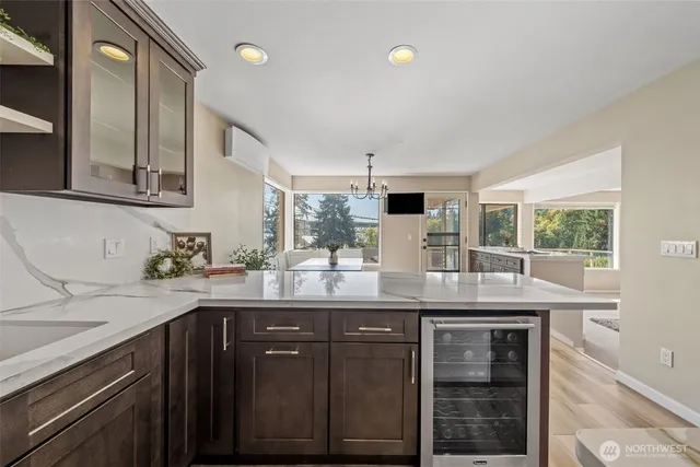 a view of a refrigerator in kitchen and an empty room with wooden floor