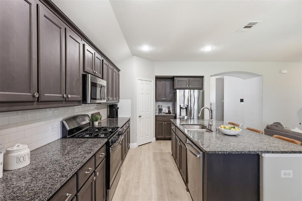 717 Allbright Road Celina, TX 75009 - Photo 8 of 37 Large island, walk in pantry, open to the living room and breakfast area, gas stove top, oven and granite counter tops