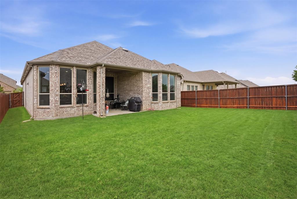 1429 Eclipse Road Aubrey, TX 76227 - Photo 25 of 37 This property features an expansive green lawn, a covered patio area, and a privacy fence