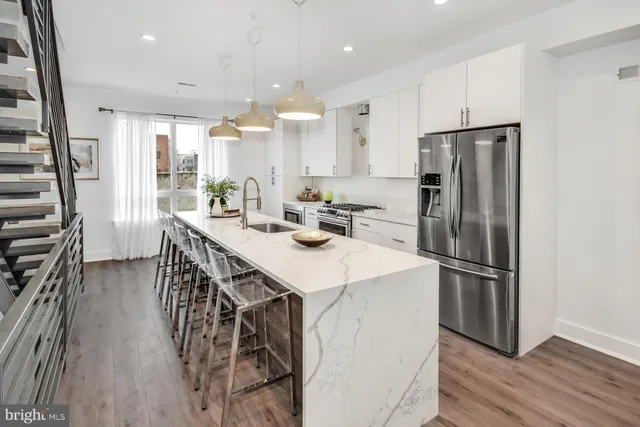 a kitchen with kitchen island a refrigerator a stove a sink and a dining table with wooden floor