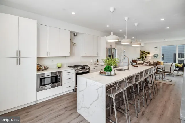a kitchen with stainless steel appliances kitchen island granite countertop a table chairs sink and cabinets