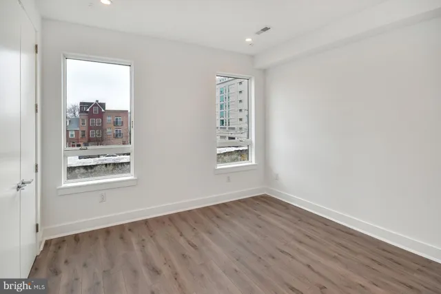 an empty room with wooden floor and windows