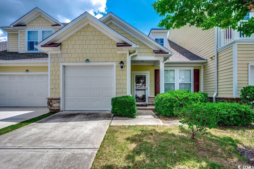 View of property with driveway, roof with shingles, and a garage