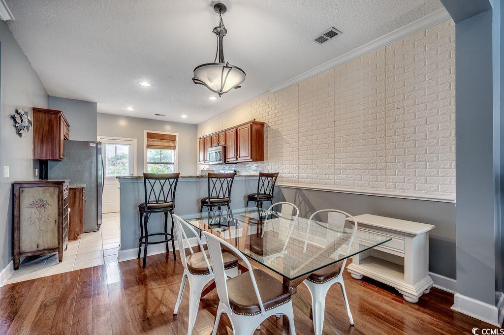 100 Culpepper Way, Unit 1002 Myrtle Beach, SC 29579 - Photo 6 of 39 Dining area featuring light wood-style flooring, a textured ceiling, and crown molding