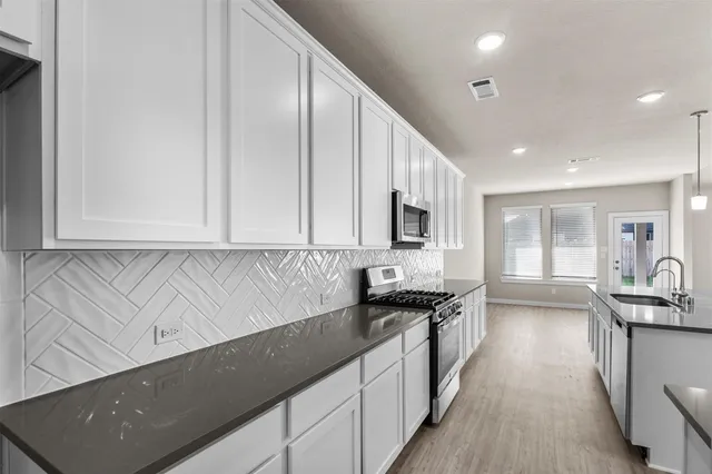 a kitchen with granite countertop a sink a stove and cabinets