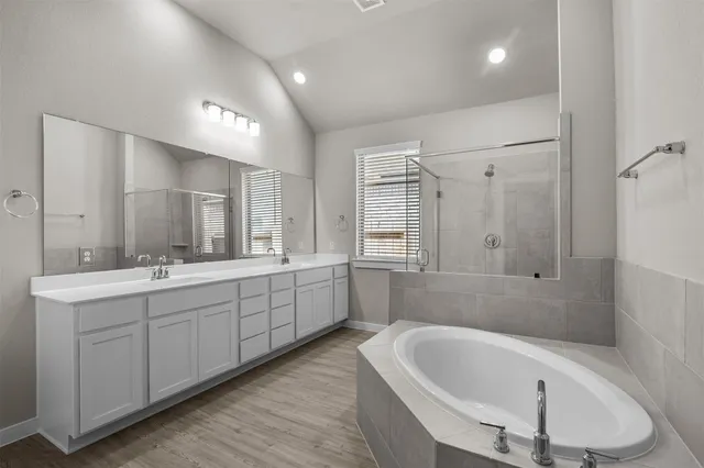 a large spacious bathroom with a tub a double vanity sink and mirror