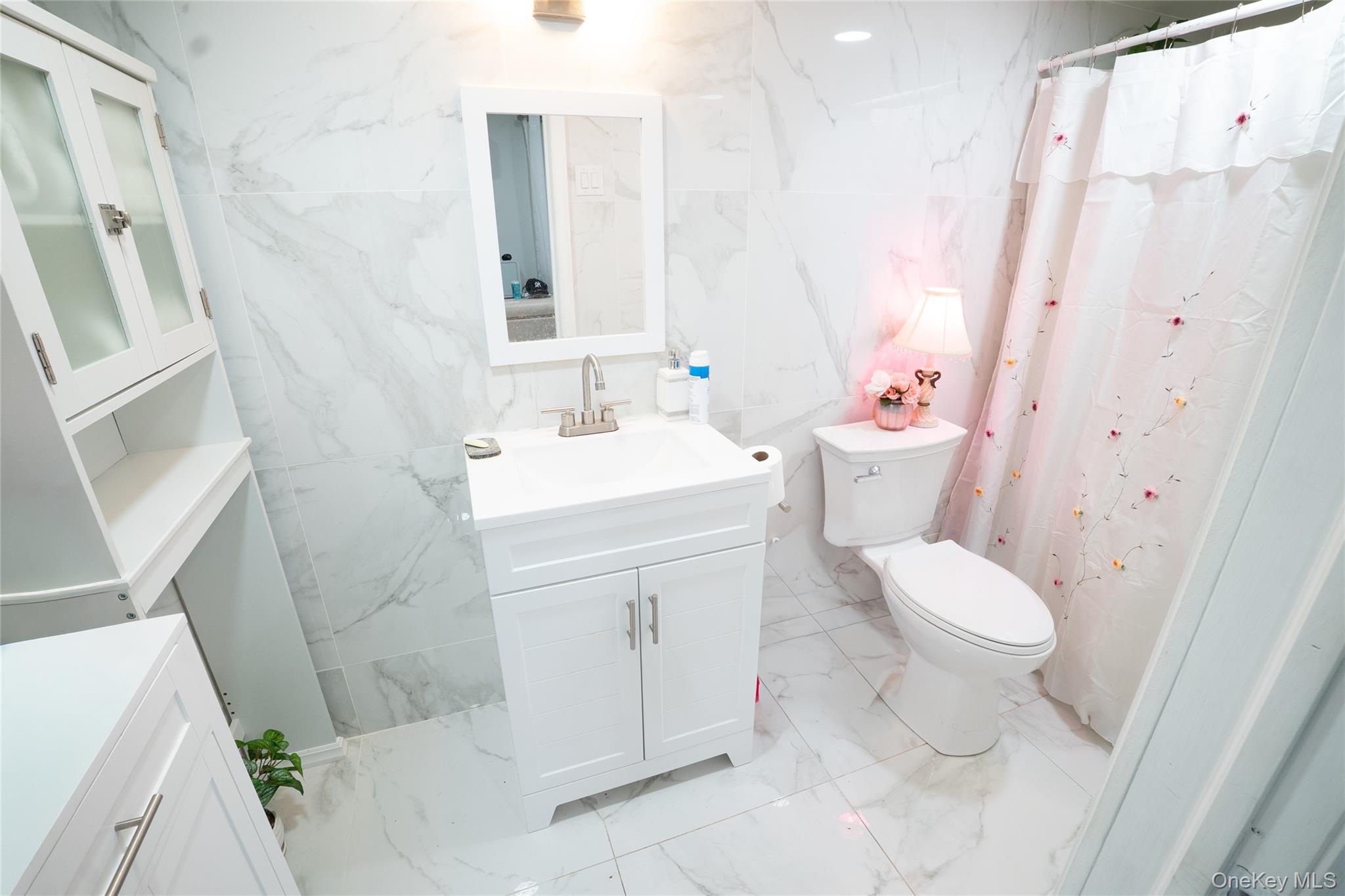 163 Orchard Road East Patchogue, NY 11772 - Photo 16 of 26 Bathroom featuring vanity, a shower with shower curtain, stone wall, light marble finish floors, and tile walls