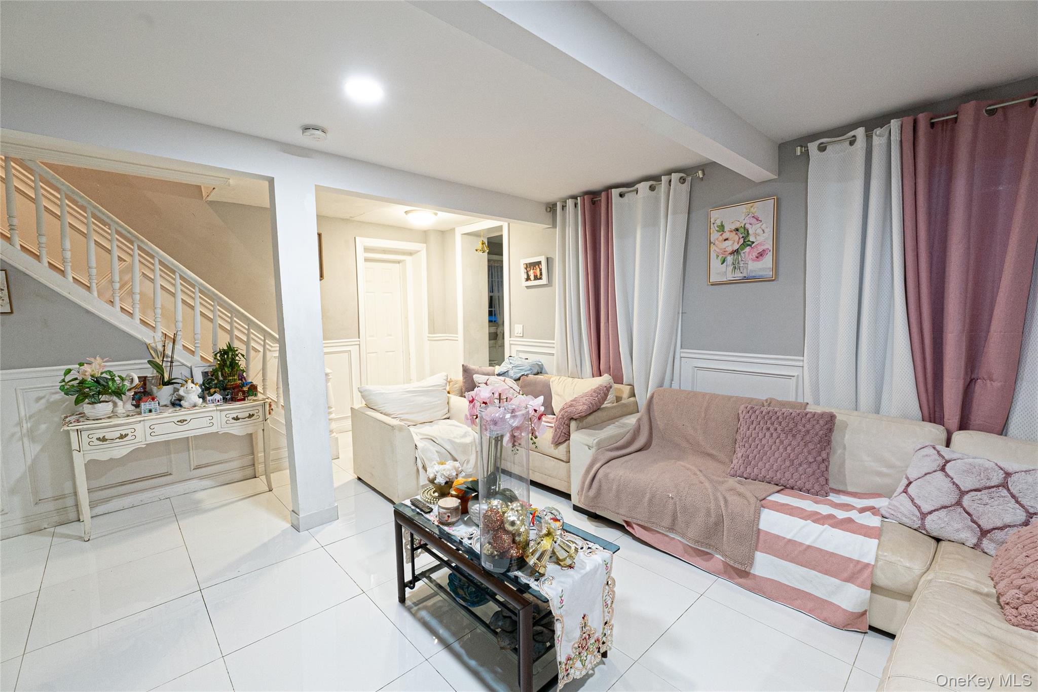 163 Orchard Road East Patchogue, NY 11772 - Photo 20 of 26 Living room with a decorative wall, a wainscoted wall, stairway, tile patterned flooring, and beam ceiling