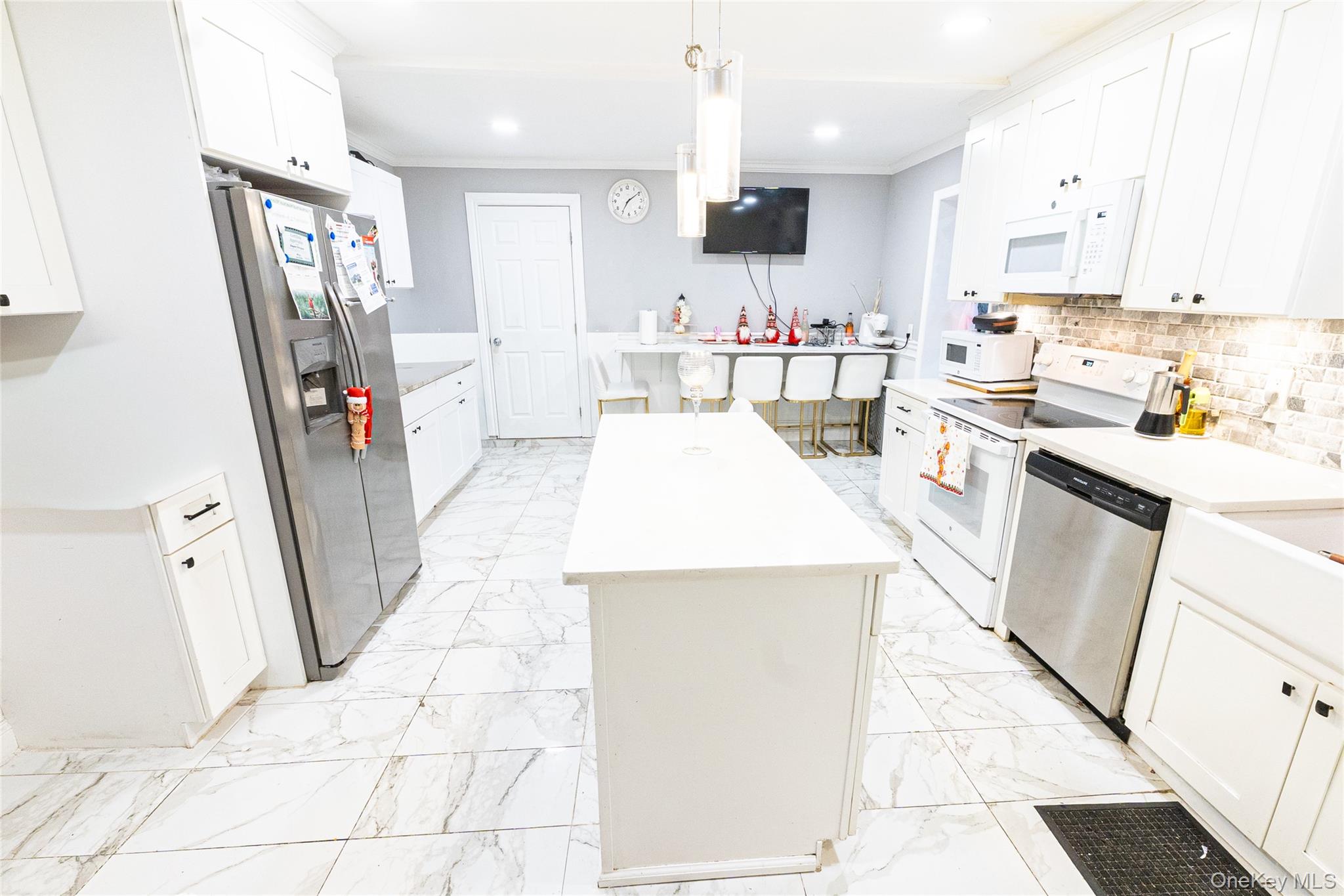 163 Orchard Road East Patchogue, NY 11772 - Photo 6 of 26 Kitchen with a kitchen island, stainless steel appliances, white cabinetry, hanging light fixtures, and crown molding