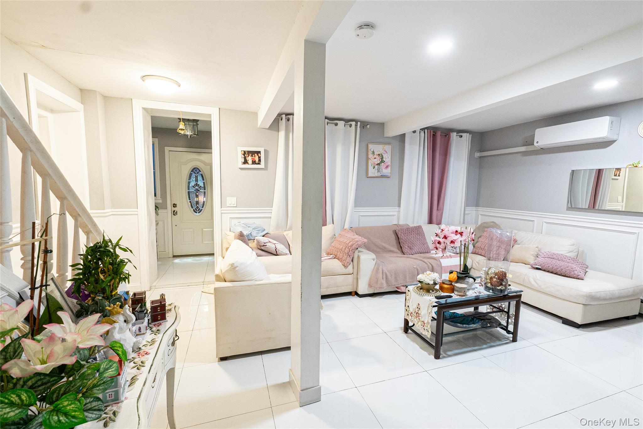 163 Orchard Road East Patchogue, NY 11772 - Photo 10 of 26 Living area with a decorative wall, a wainscoted wall, light tile patterned floors, a wall unit AC, and stairway