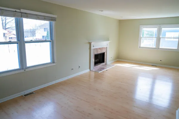 a view of empty room with wooden floor and fireplace