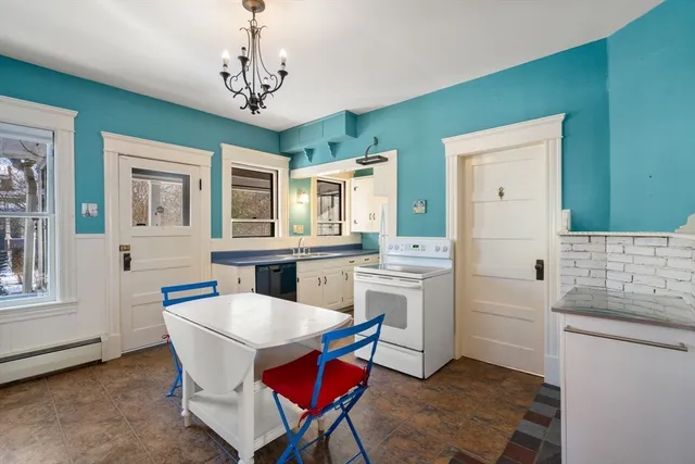 a kitchen with stainless steel appliances kitchen island granite countertop a dining table chairs and a refrigerator