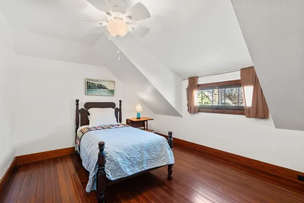 a bedroom with a bed and a large window with wooden floor
