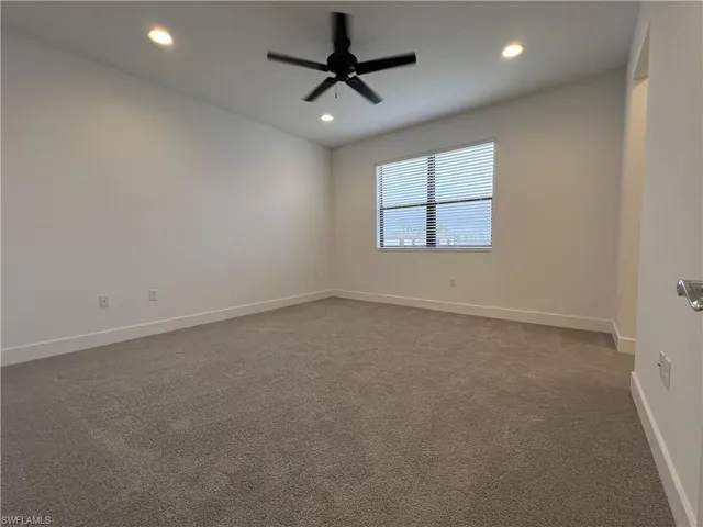 an empty room with a chandelier fan and windows