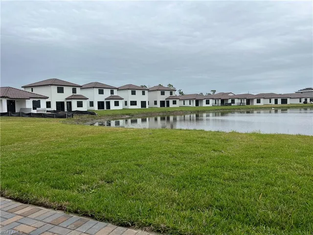 a view of a lake with a big yard and large trees