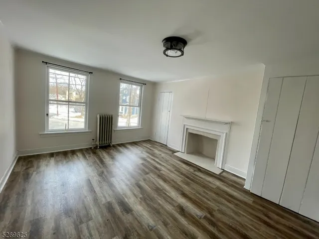 an empty room with windows and fireplace