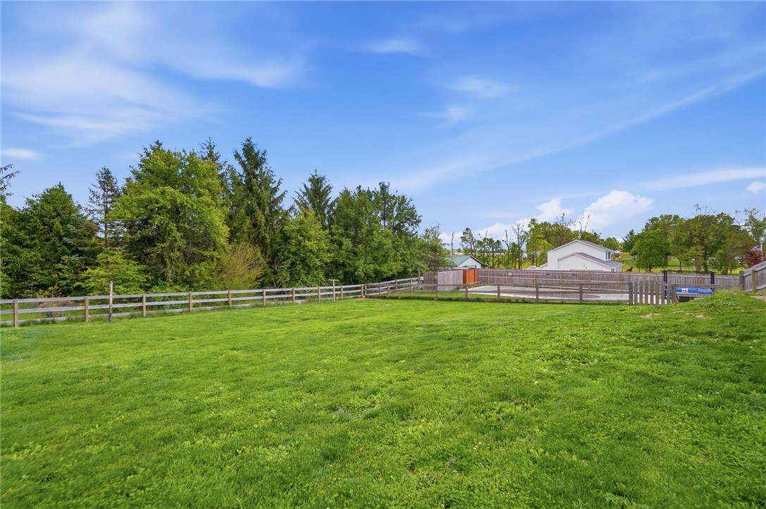 5209 North Addison New Carlisle Road St. Paris, OH 43072 - Photo 43 of 47 Expansive green lawn with a classic wooden fence, perfect for outdoor enjoyment.